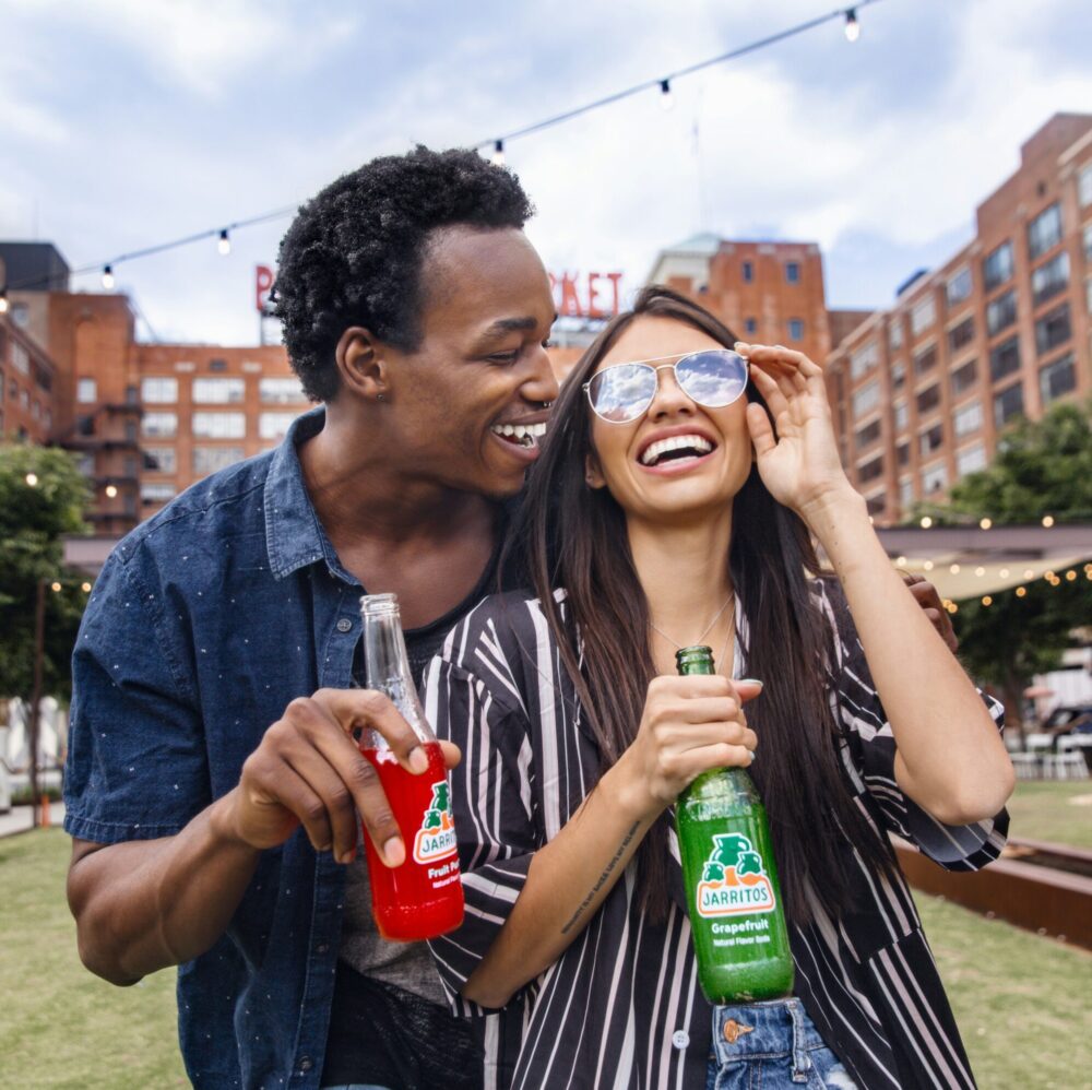 Two people smiling outside with drinks in their hands